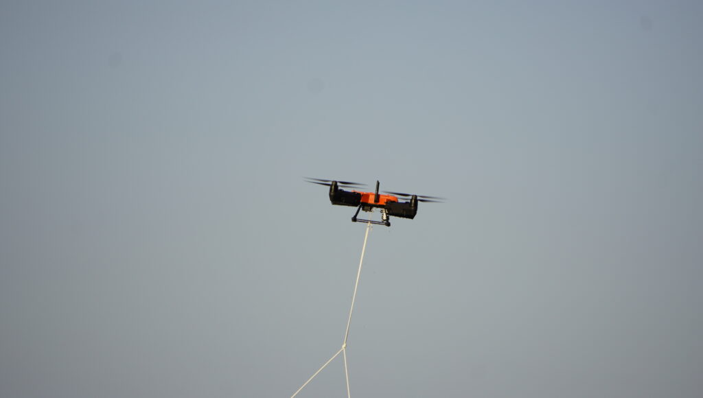 In flight against an open sky with a bait line trailing below